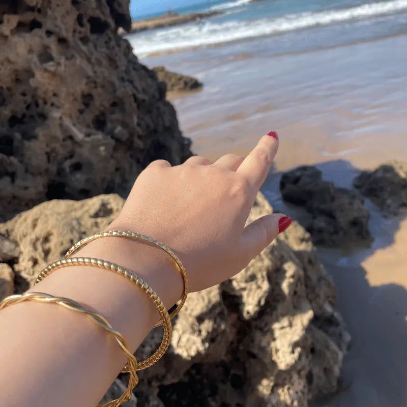 Main ornée de bracelets en acier inoxydable avec vue sur la plage