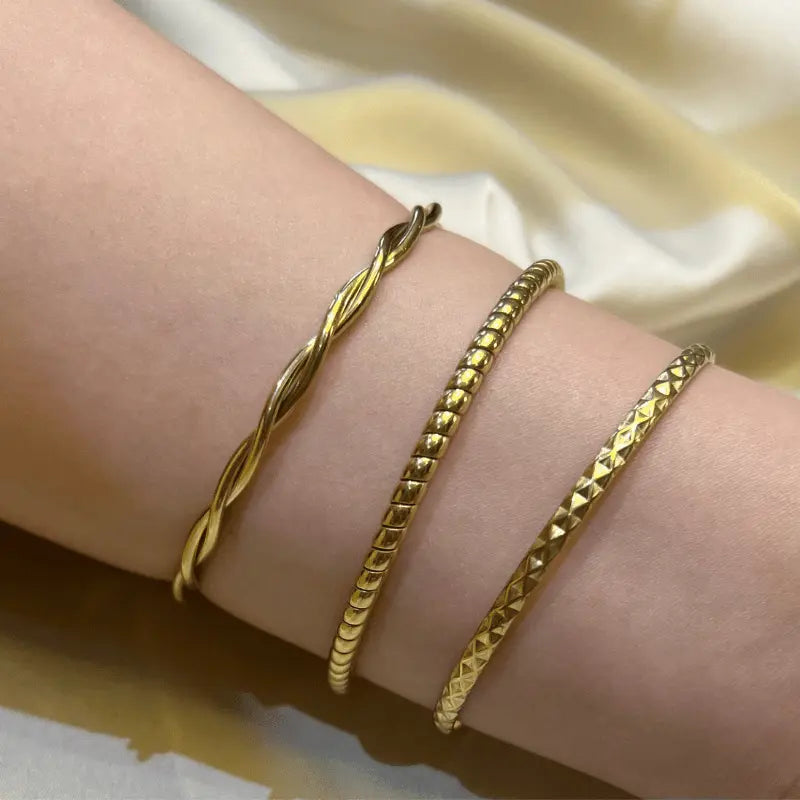 Ensemble de trois bracelets en acier inoxydable portés au poignet, idéals pour un look minimaliste et raffiné.